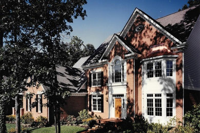 Example of a large classic red two-story brick gable roof design in Detroit