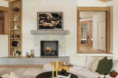 Modelo de salón abierto clásico renovado grande con paredes blancas, suelo de madera clara, marco de chimenea de yeso, televisor colgado en la pared, suelo beige y madera