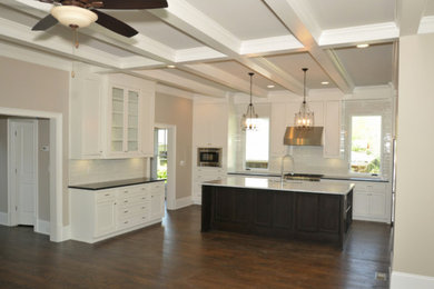 Open concept kitchen - large transitional l-shaped dark wood floor and brown floor open concept kitchen idea in Atlanta with a farmhouse sink, shaker cabinets, white cabinets, quartzite countertops, white backsplash, ceramic backsplash, stainless steel appliances and an island