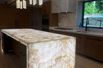 Example of a mid-sized minimalist laminate floor kitchen design in Chicago with an undermount sink, recessed-panel cabinets, brown cabinets, quartzite countertops, multicolored backsplash, stone slab backsplash, stainless steel appliances, an island and multicolored countertops