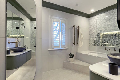 Large contemporary master bathroom in Sydney with shaker cabinets, green cabinets, an undermount tub, a shower/bathtub combo, a wall-mount toilet, white tile, porcelain tile, multi-coloured walls, porcelain floors, a vessel sink, engineered quartz benchtops, beige floor, a hinged shower door, white benchtops, a niche, a single vanity and a freestanding vanity.