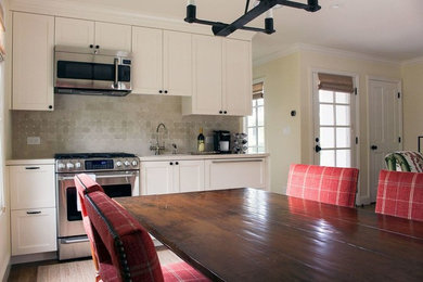 Inspiration for a small timeless single-wall medium tone wood floor and brown floor open concept kitchen remodel in Denver with an undermount sink, recessed-panel cabinets, white cabinets, marble countertops, beige backsplash, stone tile backsplash and stainless steel appliances