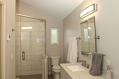 Inspiration for a mid-sized transitional master bathroom in Indianapolis with recessed-panel cabinets, a corner shower, ceramic tile, grey walls, porcelain floors, a drop-in sink, brown floor and a hinged shower door.