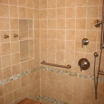 Shower area with bench and easy-to-reach controls, towel hooks, and niches