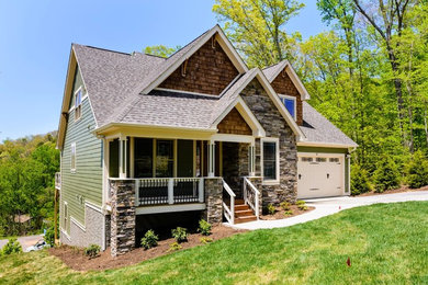 This is an example of a country two-storey green exterior in Charlotte with stone veneer.