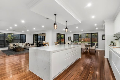 This is an example of a transitional kitchen in Melbourne with with island, flat-panel cabinets and white cabinets.