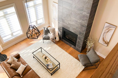 Family room - large open concept medium tone wood floor and brown floor family room idea in Toronto with beige walls, a standard fireplace, a stone fireplace and a wall-mounted tv