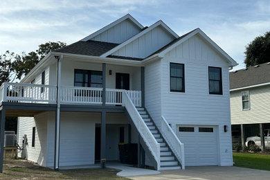 Inspiration for a large white two-story vinyl and board and batten exterior home remodel in Other with a shingle roof and a black roof