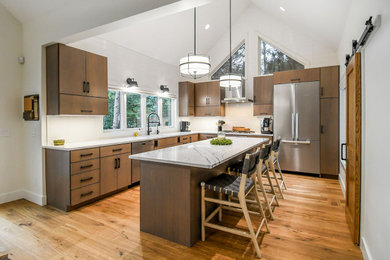 Minimalist u-shaped medium tone wood floor and vaulted ceiling eat-in kitchen photo in Minneapolis with flat-panel cabinets, medium tone wood cabinets, quartz countertops, white backsplash, subway tile backsplash, stainless steel appliances, an island and white countertops