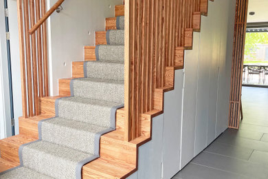 エセックスにあるラグジュアリーな広いモダンスタイルのおしゃれな階段 (木材の手すり) の写真