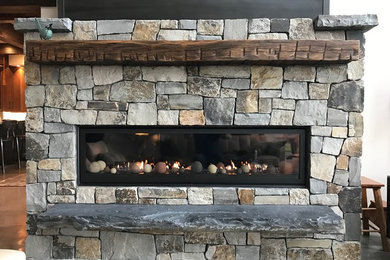 Example of a mountain style living room design in Other with a stone fireplace