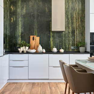 Moderne Wohnküche ohne Insel in L-Form mit flächenbündigen Schrankfronten, weißen Schränken, Küchenrückwand in Grün, Rückwand aus Stein, braunem Boden und schwarzer Arbeitsplatte in Moskau