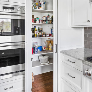 Inredning av ett klassiskt mellanstort beige beige kök, med en undermonterad diskho, skåp i shakerstil, vita skåp, bänkskiva i kvarts, beige stänkskydd, stänkskydd i porslinskakel, rostfria vitvaror, mellanmörkt trägolv, en köksö och brunt golv