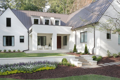 Large transitional white two-story brick gable roof photo in Atlanta with a metal roof