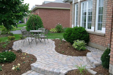 Photo of a mid-sized contemporary front yard patio in Toronto with natural stone pavers and no cover.