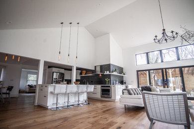 Example of a huge trendy open concept medium tone wood floor living room design in New York with white walls and a wall-mounted tv