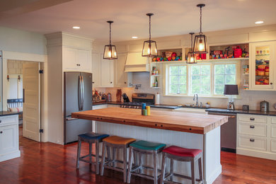 Inspiration for a timeless l-shaped medium tone wood floor kitchen remodel in Other with a farmhouse sink, beaded inset cabinets, white backsplash, subway tile backsplash and an island
