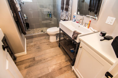 Inspiration for a mid-sized contemporary kids' medium tone wood floor doorless shower remodel in Orange County with a console sink, recessed-panel cabinets, white cabinets, a one-piece toilet and beige walls
