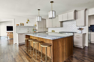 Example of a large trendy l-shaped medium tone wood floor and brown floor eat-in kitchen design in Dallas with an undermount sink, shaker cabinets, beige cabinets, quartzite countertops, white backsplash, porcelain backsplash, stainless steel appliances, an island and multicolored countertops