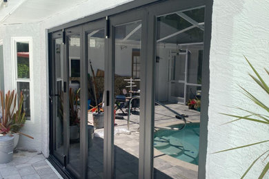 Huge trendy backyard concrete paver patio photo in Tampa with a roof extension