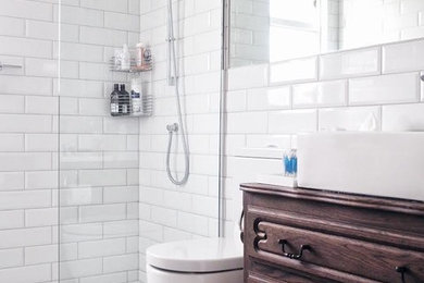 This is an example of a contemporary bathroom in London with brown cabinets, an open shower, a one-piece toilet, white tile, ceramic tile, white walls, multi-coloured floor, an open shower and terrazzo floors.