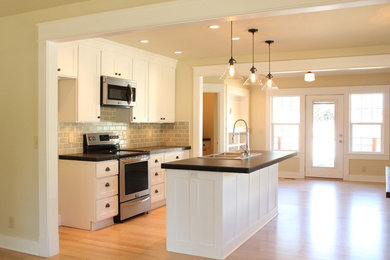 Inspiration for a craftsman light wood floor eat-in kitchen remodel in Seattle with a drop-in sink, shaker cabinets, white cabinets, tile countertops, gray backsplash, subway tile backsplash, stainless steel appliances and an island