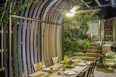Large trendy backyard concrete paver patio fountain photo in DC Metro with a pergola