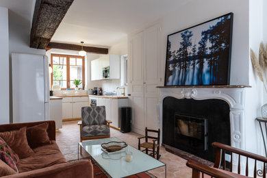 ルアーブルにある高級な中くらいなトランジショナルスタイルのおしゃれなLDK (白い壁、テラコッタタイルの床、標準型暖炉、石材の暖炉まわり、据え置き型テレビ、ピンクの床、表し梁) の写真
