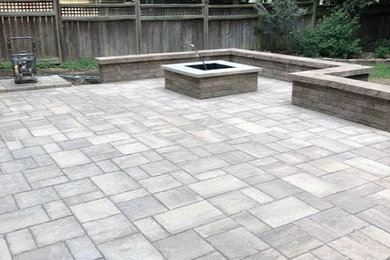 Example of a large transitional backyard stamped concrete patio design in Raleigh with a fire pit and no cover