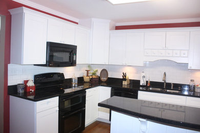 Open concept kitchen - mid-sized traditional l-shaped medium tone wood floor open concept kitchen idea in Cincinnati with a double-bowl sink, recessed-panel cabinets, white cabinets, granite countertops, white backsplash, subway tile backsplash, black appliances and an island