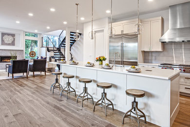 Eat-in kitchen - large transitional l-shaped medium tone wood floor and brown floor eat-in kitchen idea in Seattle with an undermount sink, shaker cabinets, gray cabinets, quartz countertops, gray backsplash, glass tile backsplash, stainless steel appliances, an island and white countertops