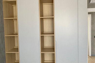 Diseño de armario y vestidor unisex de tamaño medio con a medida, armarios con paneles lisos, puertas de armario grises, suelo laminado, suelo naranja y vigas vistas
