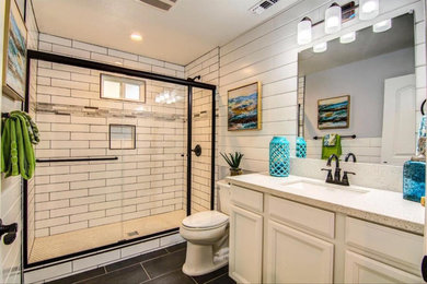 Inspiration for a mid-sized transitional 3/4 bathroom in Sacramento with recessed-panel cabinets, white cabinets, an alcove shower, a two-piece toilet, white tile, ceramic tile, white walls, slate floors, an undermount sink, grey floor and a sliding shower screen.