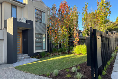 Photo of a small contemporary front yard full sun driveway for fall in Melbourne with concrete pavers, a metal fence and a garden path.