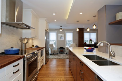 Inspiration for a transitional medium tone wood floor kitchen remodel in Ottawa with a double-bowl sink, shaker cabinets, white cabinets, quartzite countertops, beige backsplash, porcelain backsplash, stainless steel appliances and an island