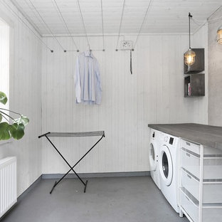 Design ideas for a scandinavian single-wall separated utility room in Stockholm with a single-bowl sink, open cabinets, white walls, a side by side washer and dryer and grey floors.