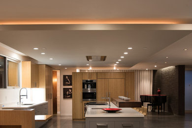 This is an example of a large modern l-shaped eat-in kitchen in Los Angeles with an undermount sink, flat-panel cabinets, grey cabinets, laminate benchtops, white splashback, stainless steel appliances, concrete floors, with island and grey floor.