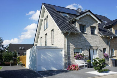 This is an example of a mid-sized country three-storey brick beige exterior in Dusseldorf with a gable roof.