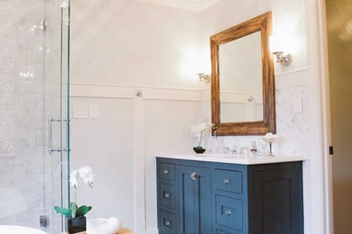 Example of a mid-sized transitional 3/4 gray tile, white tile and marble tile light wood floor and beige floor bathroom design in Charlotte with shaker cabinets, blue cabinets, white walls, an undermount sink, quartz countertops, a hinged shower door and white countertops