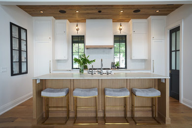 Photo of a medium sized classic kitchen in Other with a belfast sink, flat-panel cabinets, medium wood cabinets, white splashback, metro tiled splashback, integrated appliances, medium hardwood flooring, an island, brown floors, grey worktops and a wood ceiling.