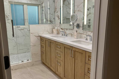 This is an example of a mid-sized contemporary bathroom in Los Angeles with shaker cabinets, medium wood cabinets, porcelain floors, solid surface benchtops, beige floor, white benchtops, a niche, a double vanity and a built-in vanity.