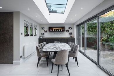 Design ideas for a mid-sized contemporary kitchen/dining combo in Berkshire with white walls, porcelain floors, grey floor and vaulted.