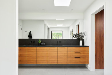 Bathroom - large modern master white tile porcelain tile, gray floor and double-sink bathroom idea in Kansas City with flat-panel cabinets, light wood cabinets, a one-piece toilet, white walls, an undermount sink, quartzite countertops, a hinged shower door, black countertops and a floating vanity