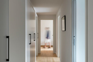 Esempio di un ingresso o corridoio design con pareti bianche, parquet chiaro e soffitto ribassato