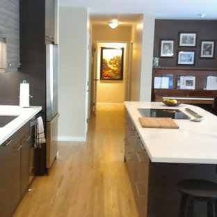 Idéer för ett mellanstort modernt kök, med en undermonterad diskho, släta luckor, skåp i mörkt trä, bänkskiva i kvartsit, grått stänkskydd, stänkskydd i glaskakel, rostfria vitvaror, ljust trägolv, en köksö och gult golv