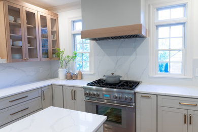 Large transitional l-shaped eat-in kitchen in New York with an undermount sink, shaker cabinets, grey cabinets, quartz benchtops, white splashback, engineered quartz splashback, stainless steel appliances, medium hardwood floors, with island, brown floor and white benchtop.