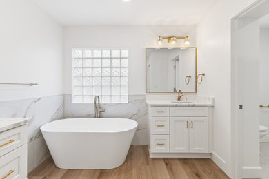 Bathroom - large master white tile and porcelain tile porcelain tile, multicolored floor and double-sink bathroom idea in Tampa with shaker cabinets, white cabinets, a one-piece toilet, white walls, an undermount sink, quartzite countertops, a hinged shower door, white countertops, a niche and a built-in vanity
