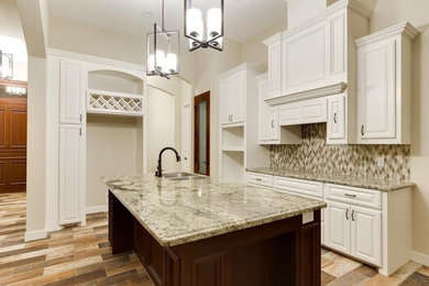 Mid-sized transitional l-shaped kitchen in Austin with a double-bowl sink, raised-panel cabinets, white cabinets, granite benchtops, multi-coloured splashback, glass tile splashback, porcelain floors, with island and brown floor.