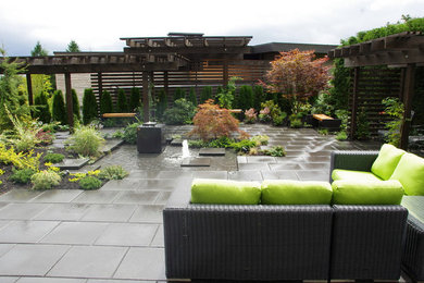 This is an example of a large contemporary courtyard full sun formal garden in Vancouver with a water feature and concrete pavers.