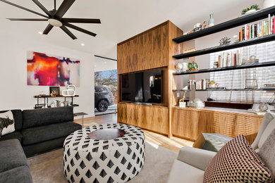 Example of a large trendy open concept light wood floor and beige floor living room design in Austin with white walls, no fireplace and a wall-mounted tv